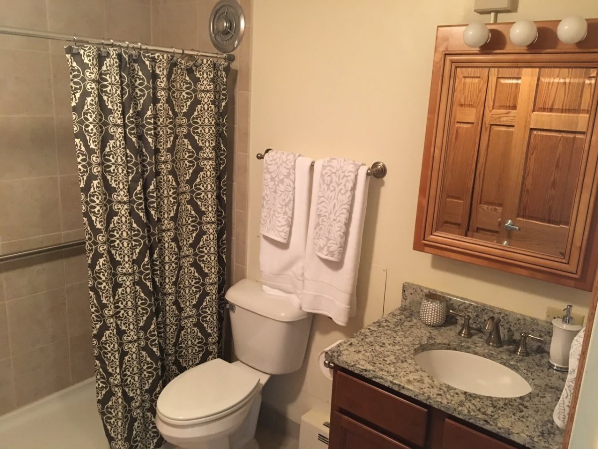 A clean and organized bathroom with a patterned shower curtain, towel rack, and granite countertop.