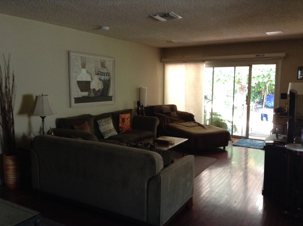 A cozy living room with sofas and a large sliding door opening to the outside.