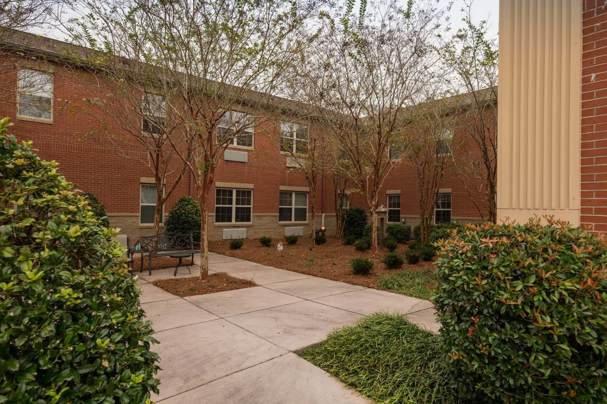 A peaceful courtyard with trees and a brick building surrounding it.