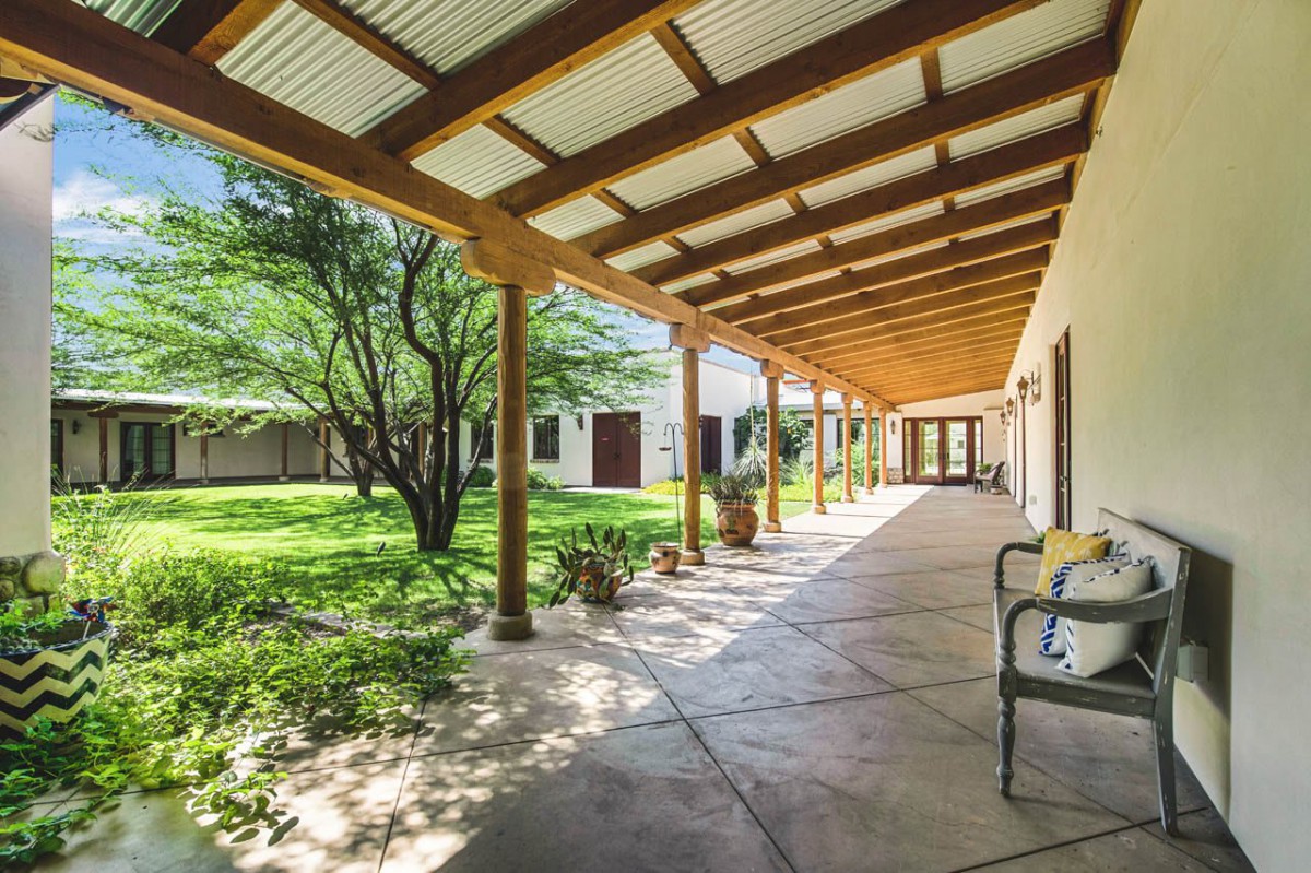 A spacious porch with wooden beams overlooking a lush garden.