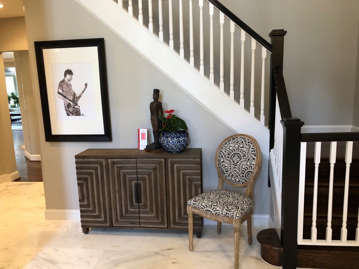 Stylish interior featuring a modern staircase with a decorative cabinet and patterned chair.