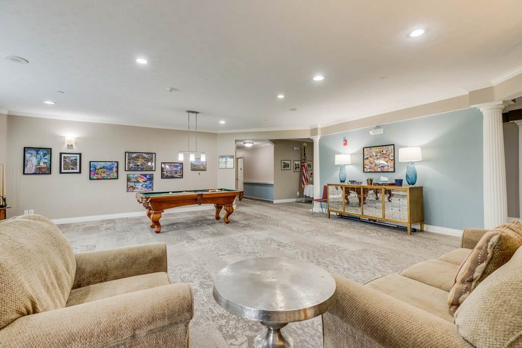 A spacious and modern game room featuring a billiards table and comfortable seating.