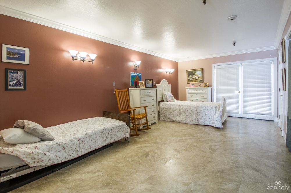 A cozy bedroom with two beds, a rocking chair, and elegant furnishings.