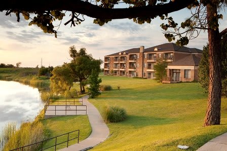 A scenic view of a lakeside building surrounded by lush greenery and a peaceful path.