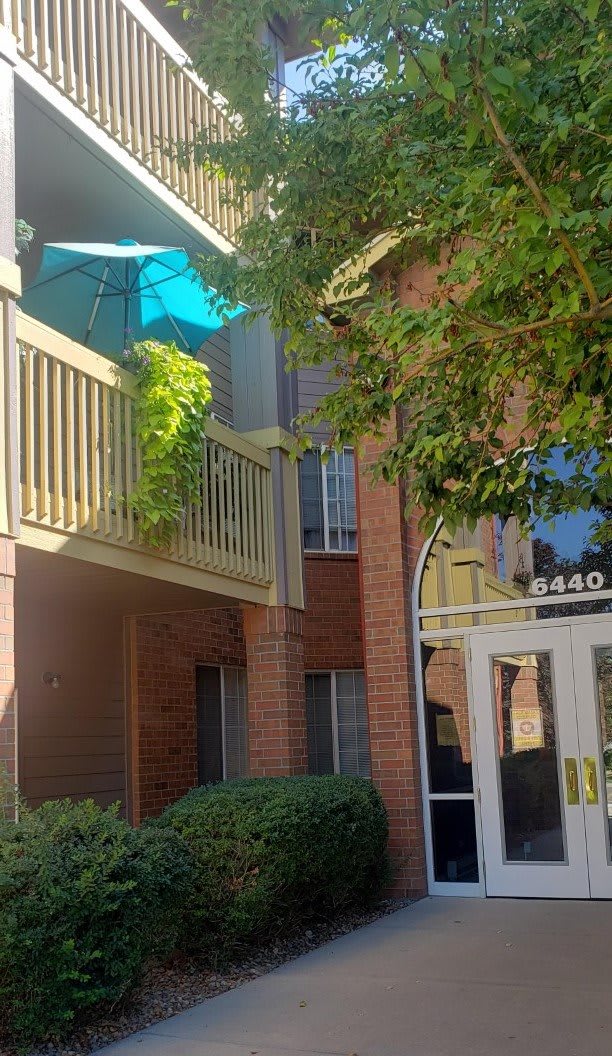 An apartment building with a balcony featuring an umbrella and plants.