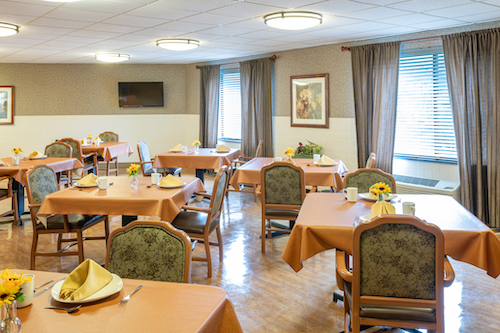 A cozy dining area set for a meal, featuring orange tablecloths and inviting decor.