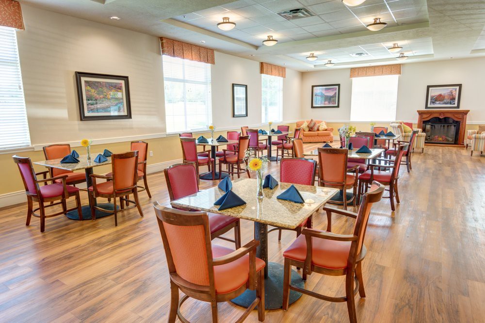 A well-lit dining room with neatly arranged tables and chairs, featuring elegant table settings.