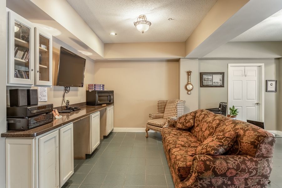 A cozy living room featuring a sofa, chairs, and a television with warm lighting.