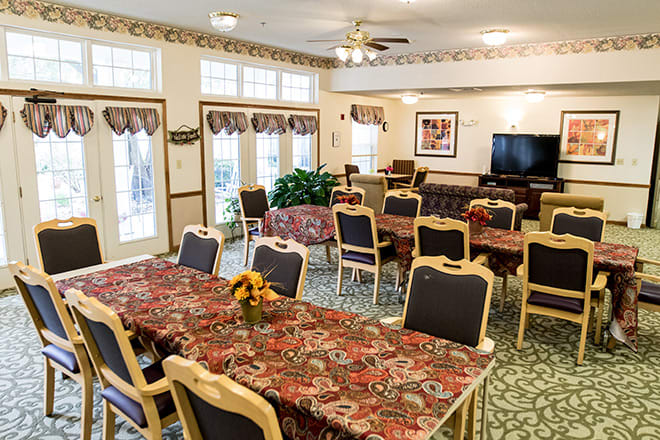 A community dining room with floral tablecloths and arranged seating.