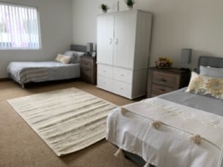 A neat and tidy bedroom with two single beds, a wardrobe, and a rug on the floor.