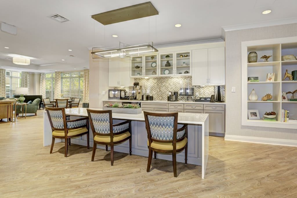 A modern kitchen with an island and bar stools, featuring stylish cabinetry and a contemporary lighting fixture.