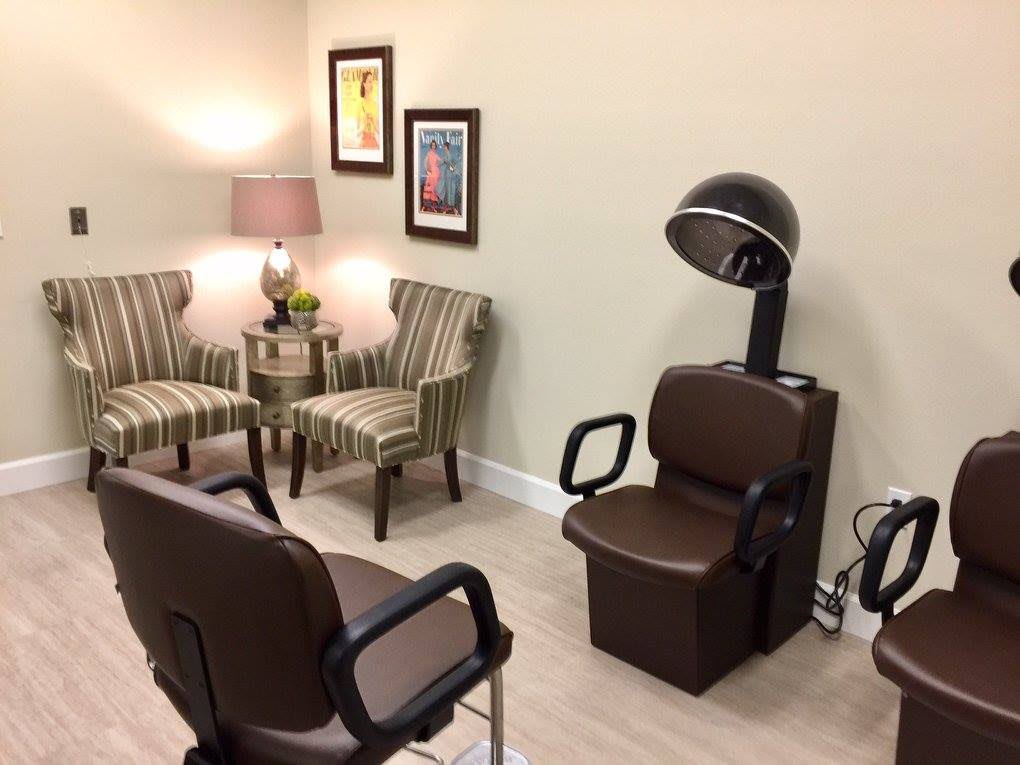 A cozy salon interior with seating and a hair dryer station.