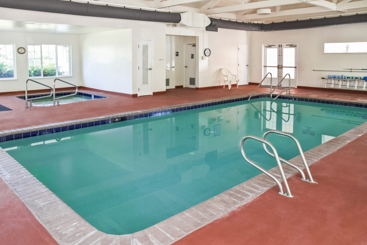 An indoor swimming pool area with clear water and surrounding lounge space.