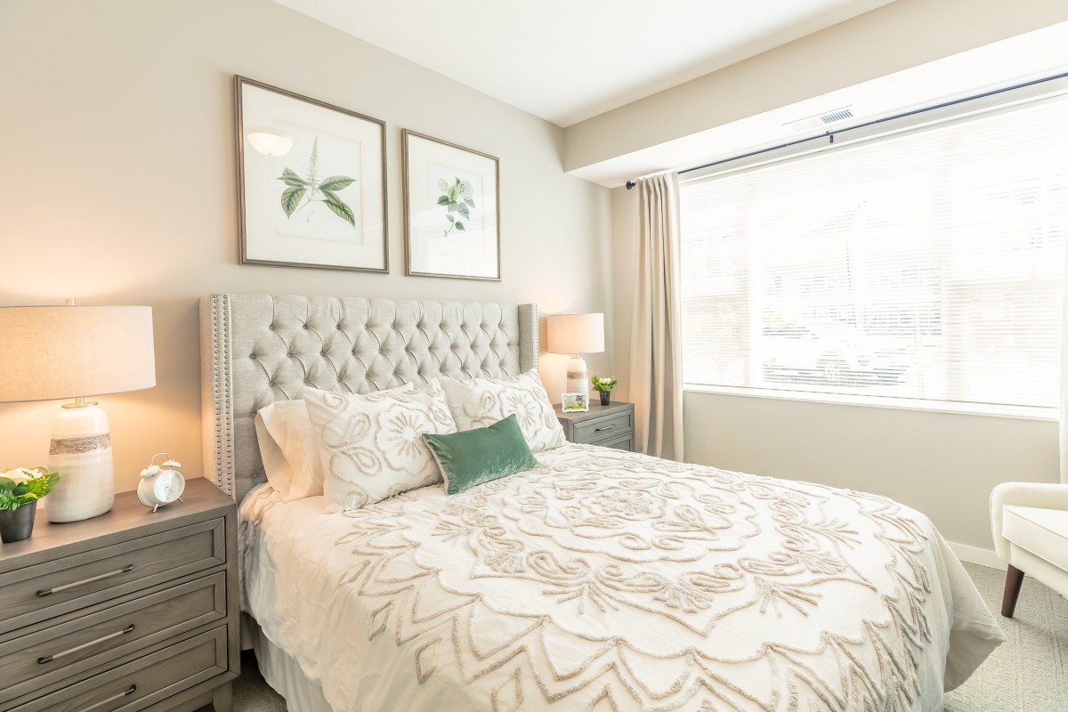 A bright and modern bedroom featuring a tufted headboard, decorative pillows, and minimalist artwork above the bed.