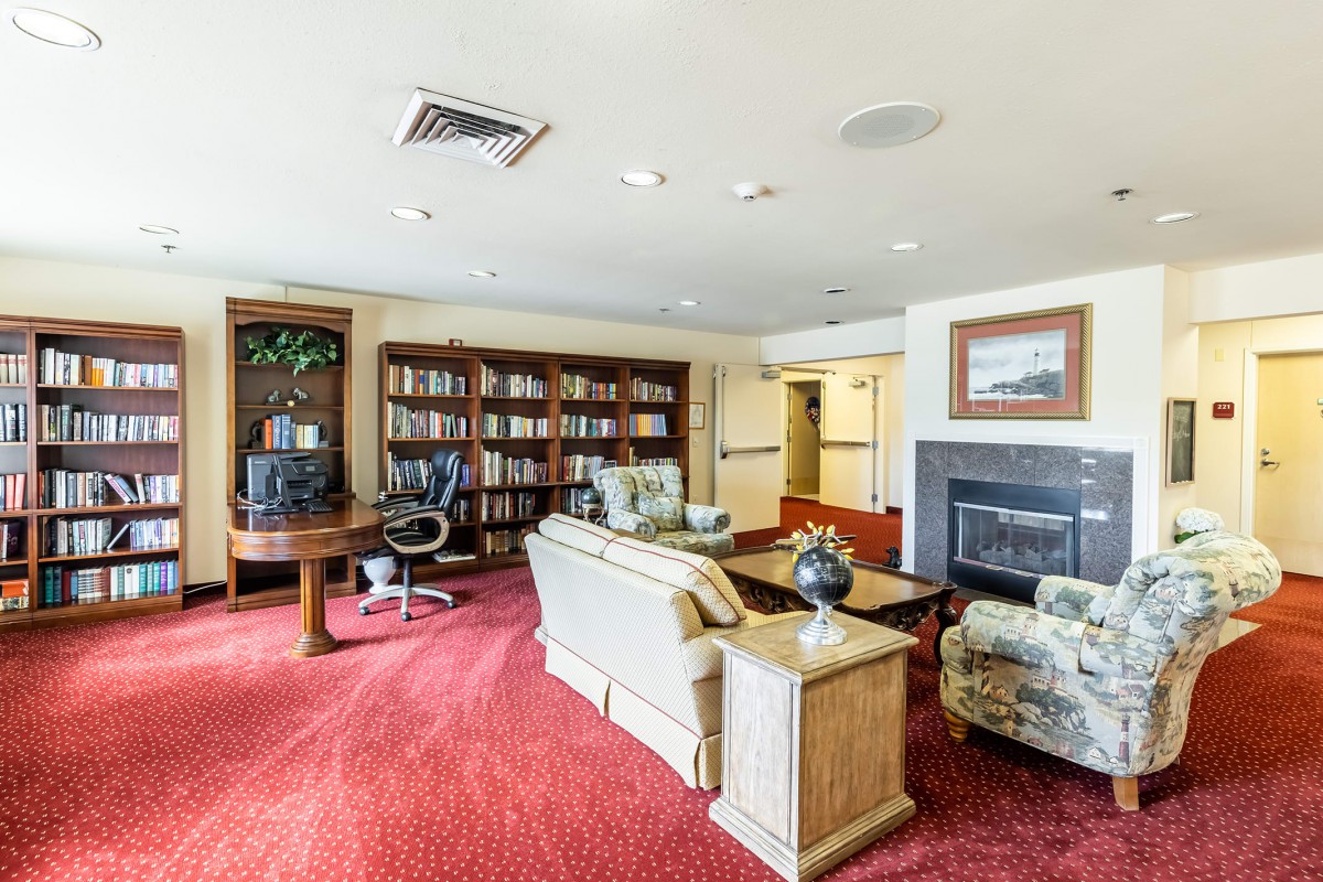 A cozy living room featuring a fireplace, bookshelf, and comfortable seating.