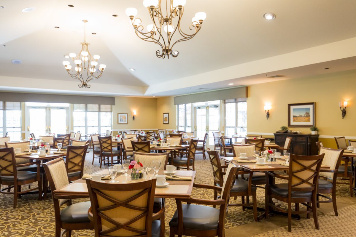 A spacious dining room with neatly arranged tables and elegant chandeliers.