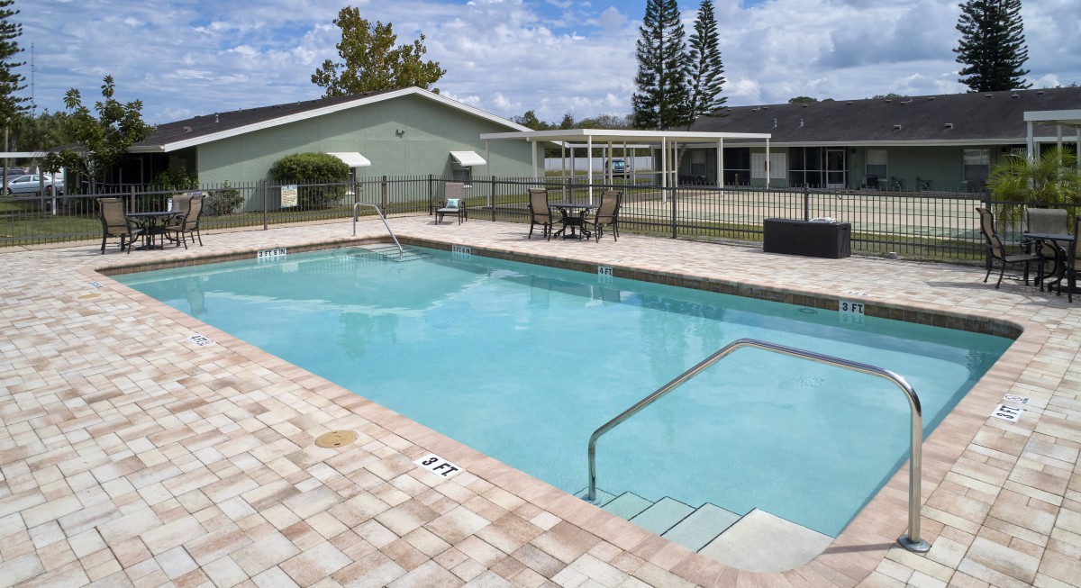 A serene outdoor swimming pool area with surrounding patio furniture and greenery.