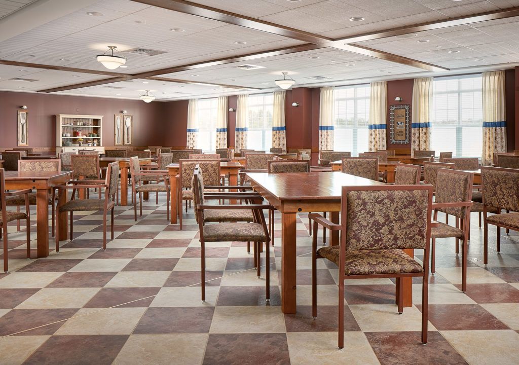 An inviting dining area with wooden tables and chairs, featuring a checkered floor and large windows.