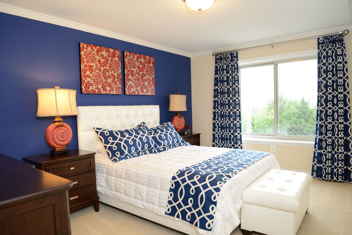 A stylish bedroom featuring blue and white decor with matching curtains and artwork.
