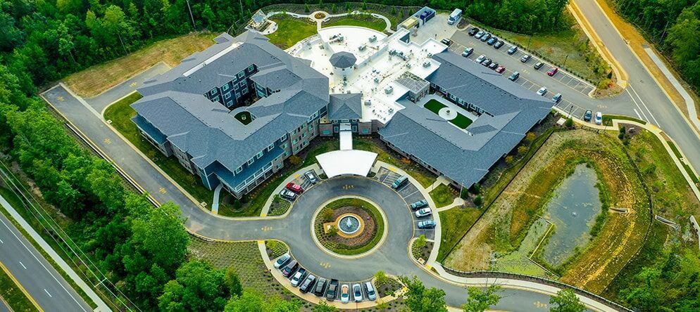 Aerial view of a large building complex with a circular driveway and parking lot.