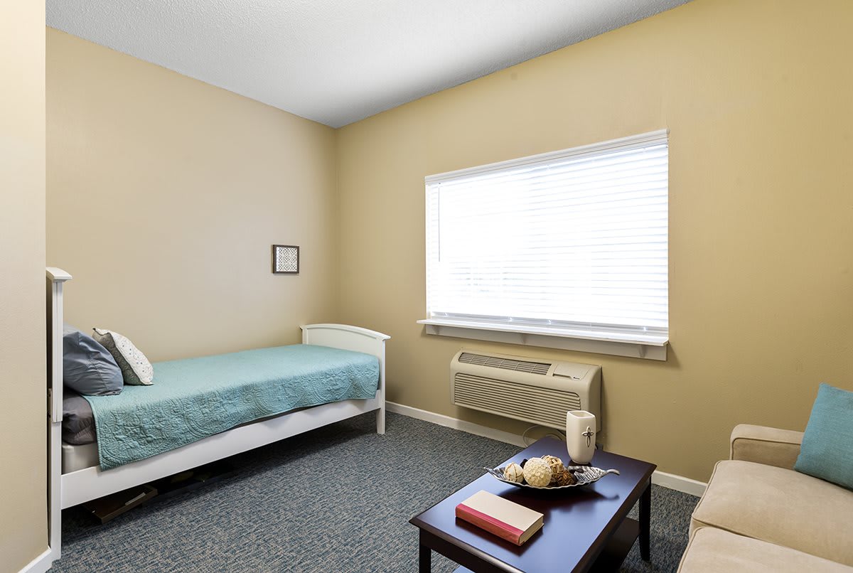 A minimalist bedroom with a single bed, small table, and neutral decor.