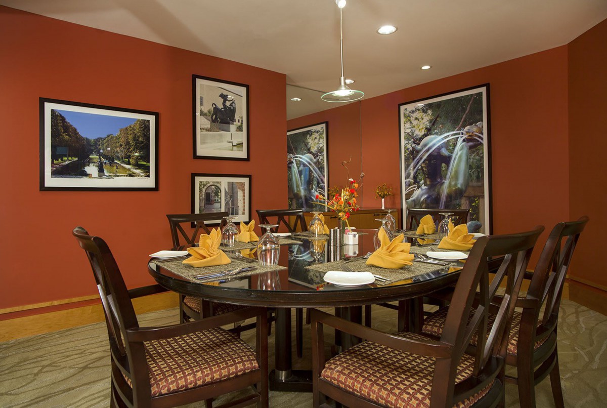 A beautifully decorated dining room with an elegant table setting and vibrant orange walls adorned with artwork.