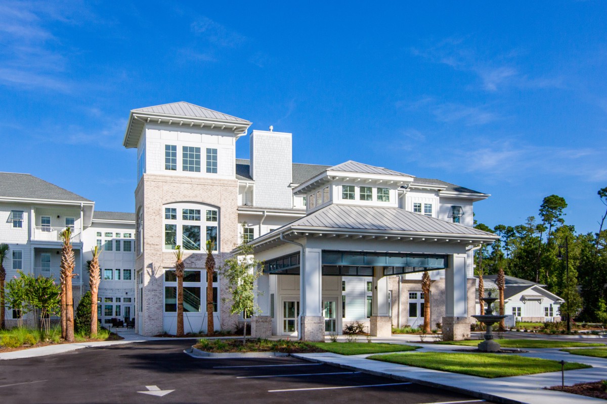 A modern residential building with a prominent entrance and clear blue skies.