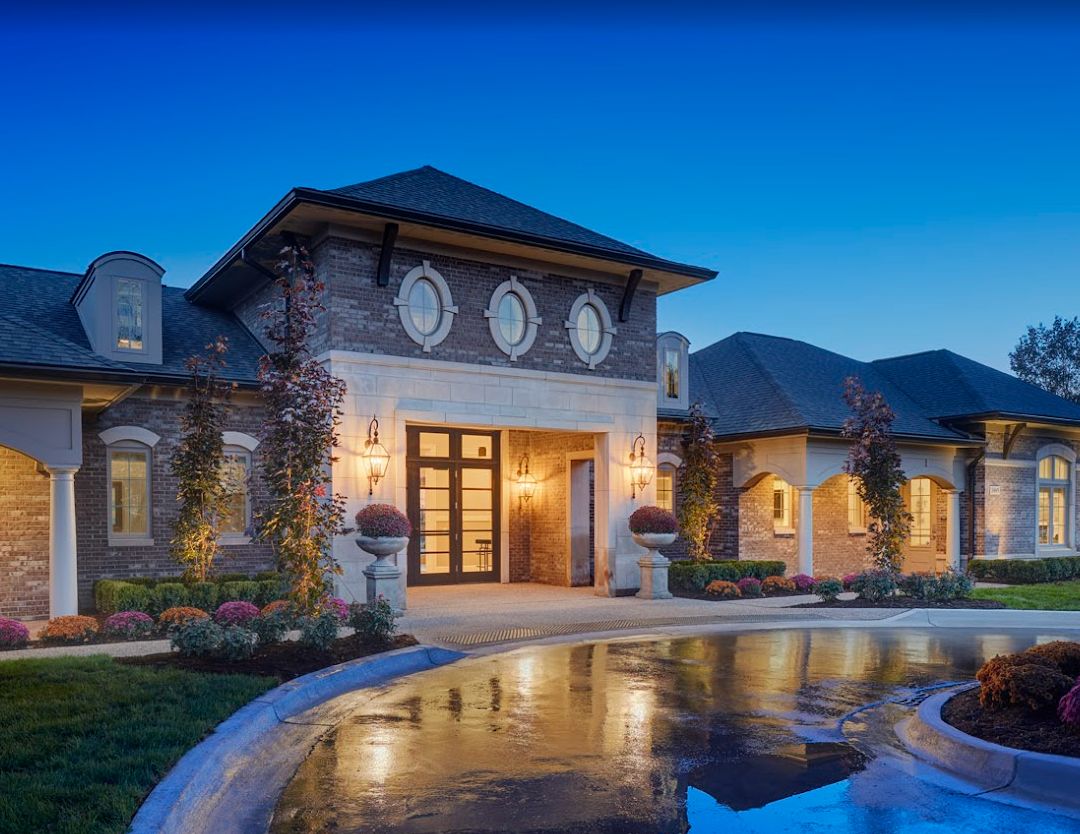 A stunning luxury mansion illuminated at dusk with elegant architectural details and beautiful landscaping.