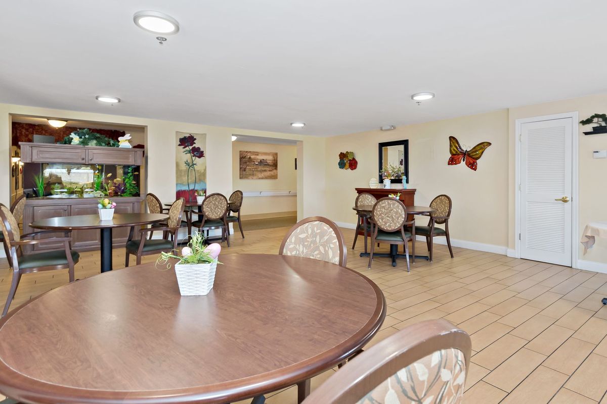 A cozy dining area with multiple tables and chairs, adorned with decorative wall art and plants.