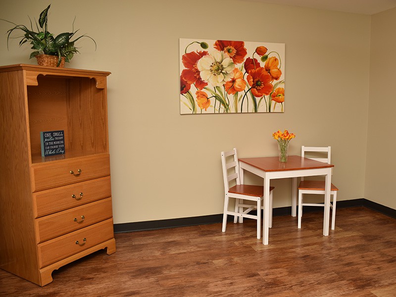 A cozy dining area featuring a small table with two chairs, complemented by vibrant floral artwork on the wall.