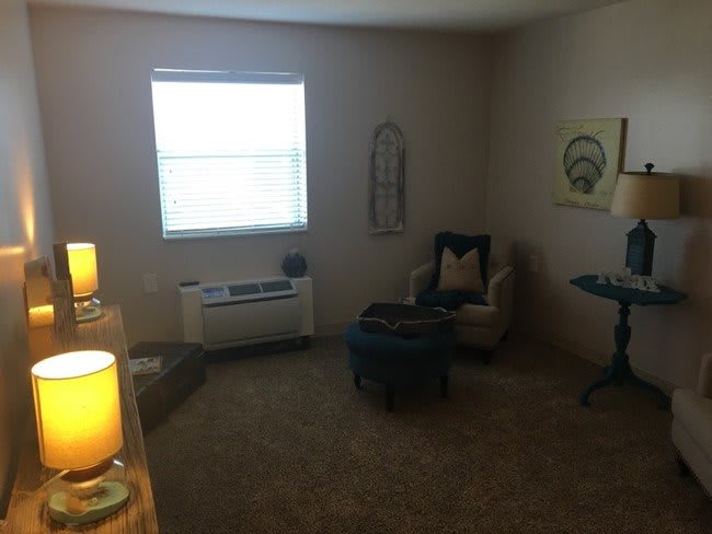 A cozy living room with an armchair, carpet, and decor.