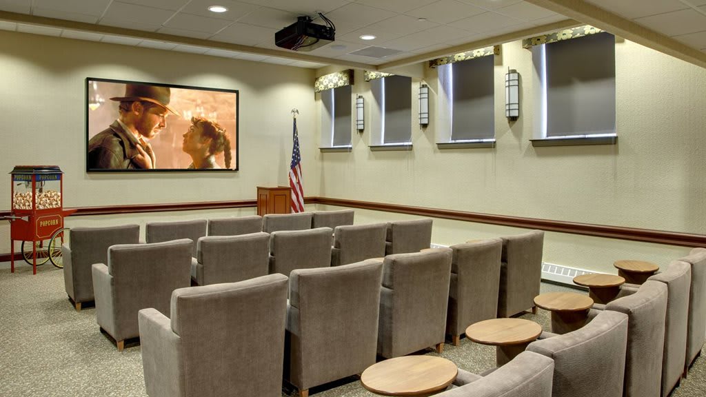 A small conference room with rows of seating and a projection screen at the front.
