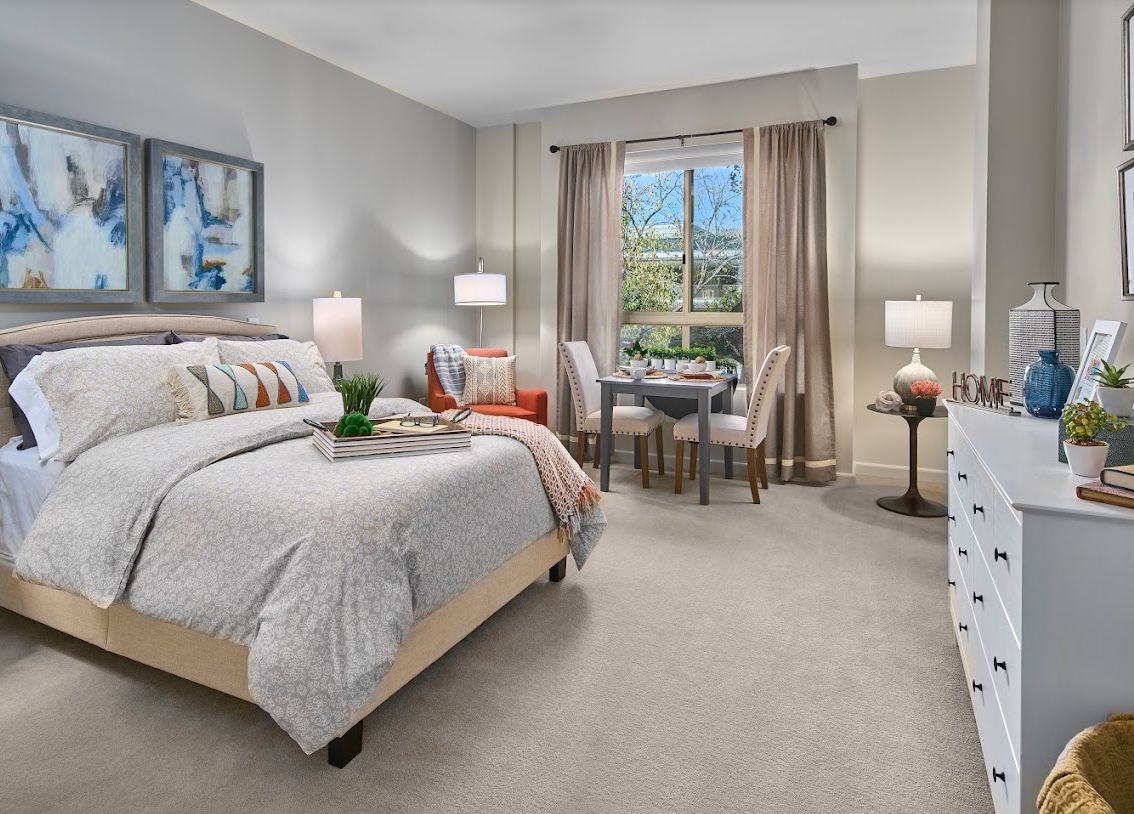 A cozy and well-decorated bedroom with a large bed, a sitting area by the window, and elegant decor.