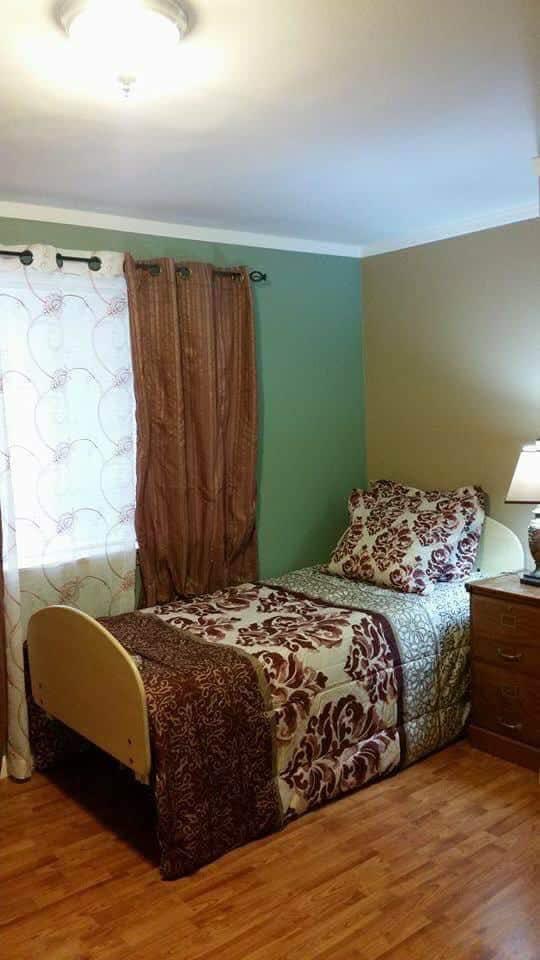 A cozy bedroom with a single bed, decorative pillows, and lamp.