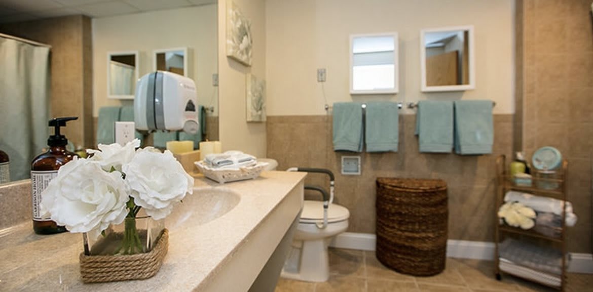 A clean and well-organized bathroom with a countertop, sink, mirror, and neatly arranged towels.