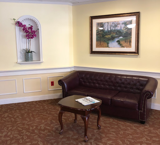 A cozy corner in a living room featuring a brown leather sofa, a small table with magazines, and decorative artwork on the walls.