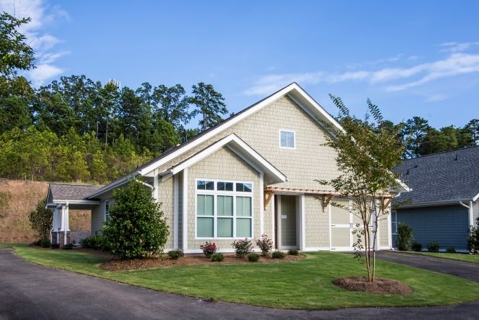 A suburban house with a neatly landscaped lawn and surrounding trees.