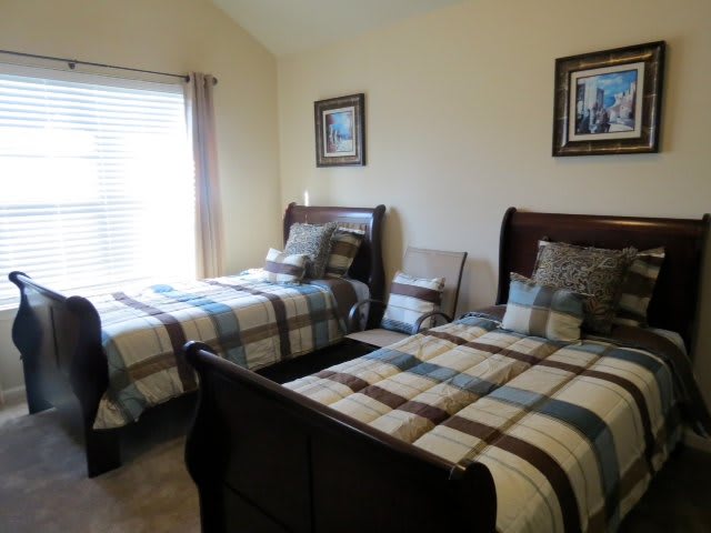 A cozy bedroom featuring two twin beds with plaid bedding and classic wooden frames.