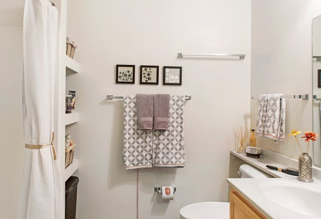 A neatly organized bathroom with towels, shelving, and decorative wall art.
