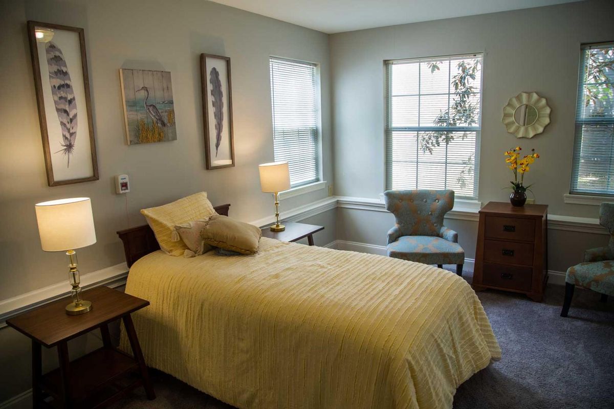 A cozy bedroom with a single bed, lamp, and window.