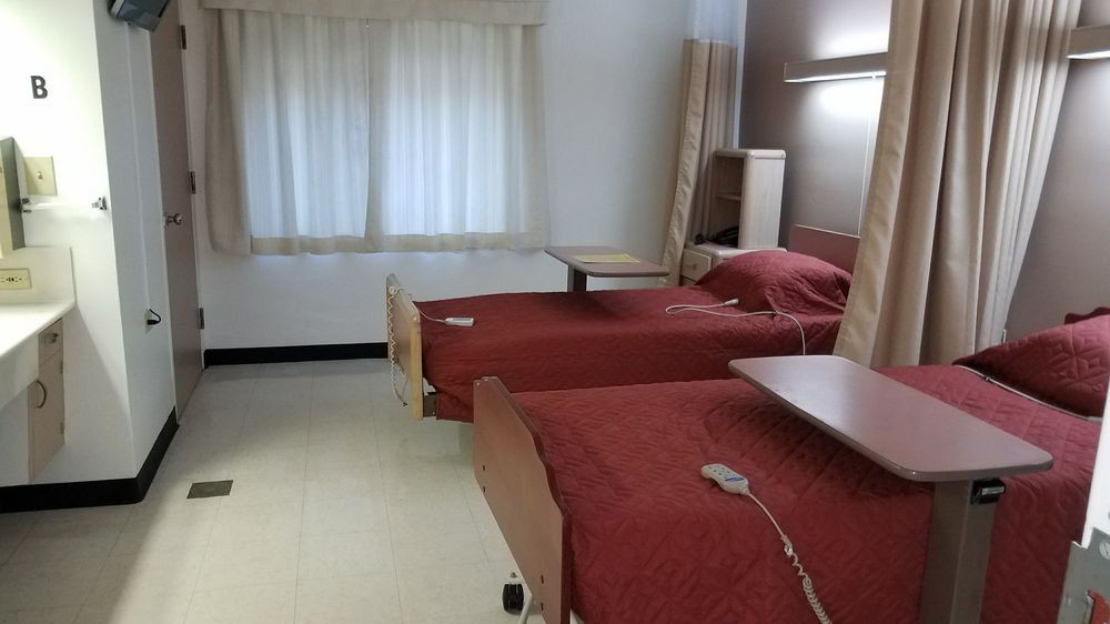 A hospital room with two beds and medical equipment.