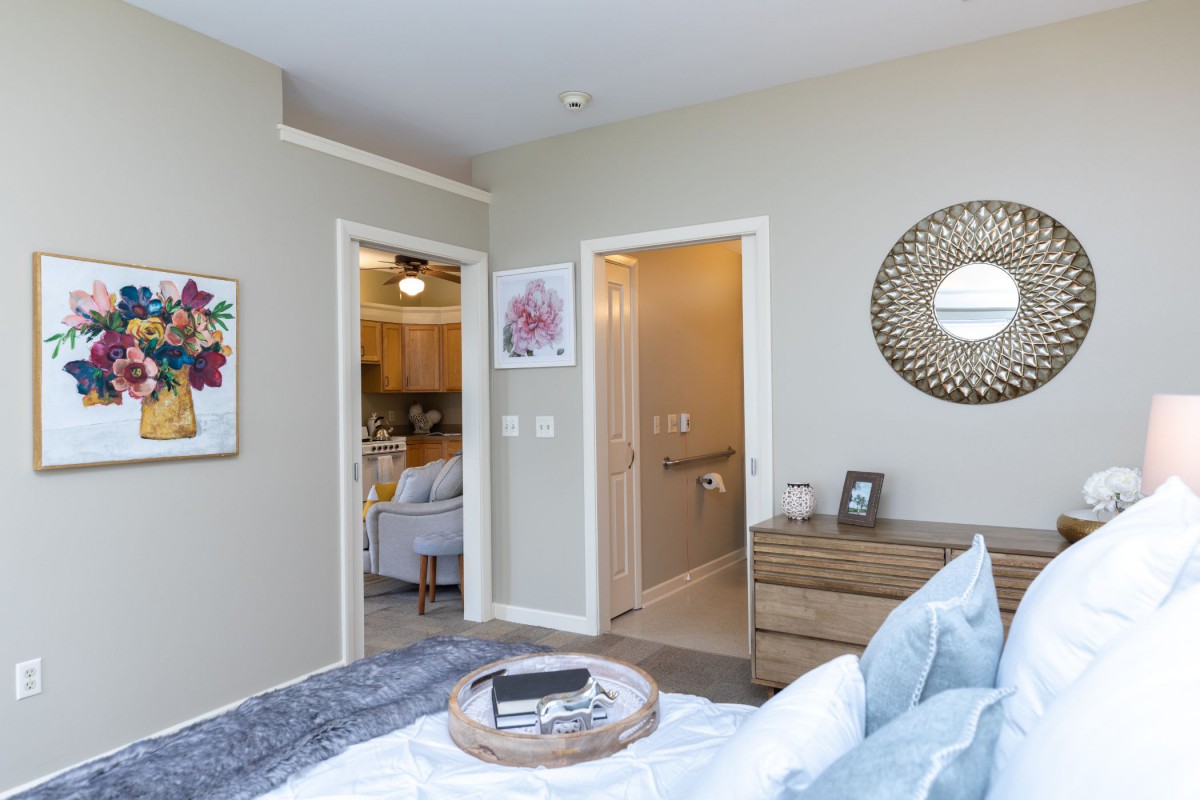 A modern bedroom interior featuring stylish decor, with a view into the adjacent hallway and living area.