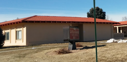A view of a building with a red tiled roof and a sign in front, set against a clear blue sky.