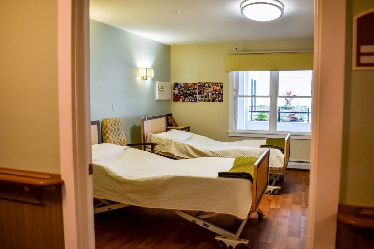 A hospital room with two patient beds and a window letting in natural light.