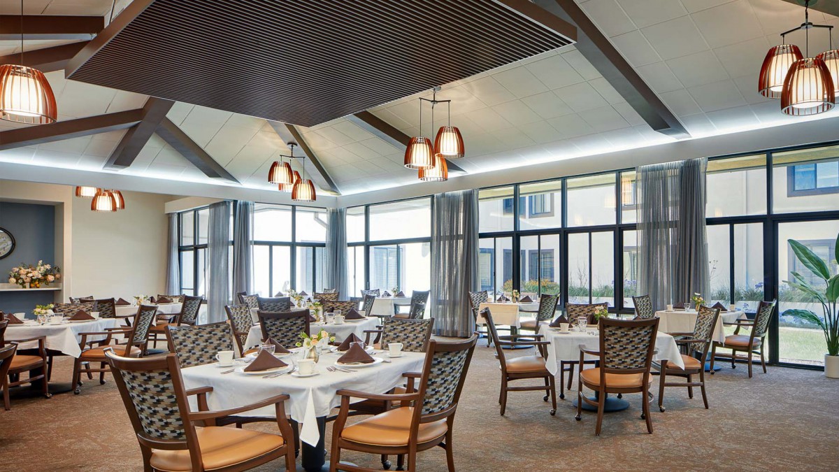 Elegant dining area with neatly arranged tables and chairs, featuring large windows and sophisticated lighting.