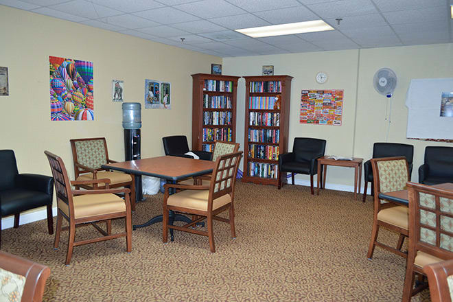 A cozy office waiting room with chairs, a table, and bookshelves filled with books.