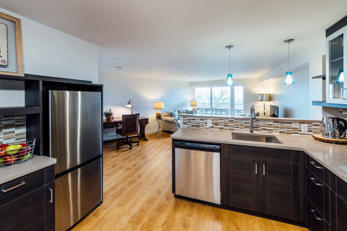 A modern open-layout kitchen with stainless steel appliances and a cozy living area.