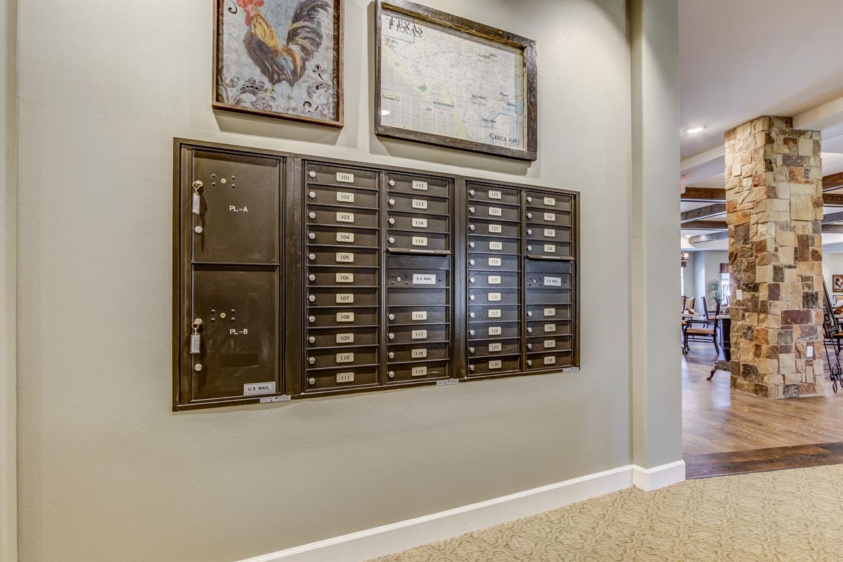 Wall-mounted mailboxes in a hallway with decorative artwork above.