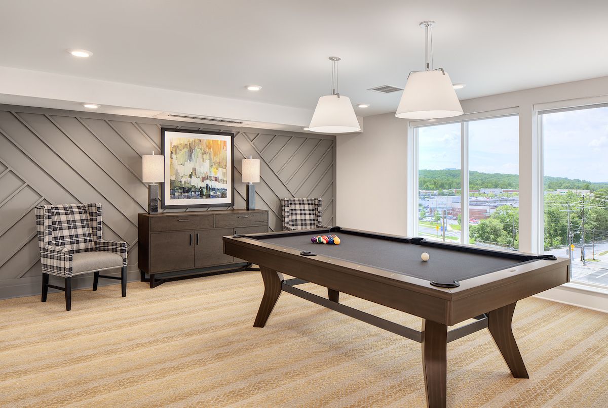 A stylish game room featuring a pool table, modern decor, and ample natural light.