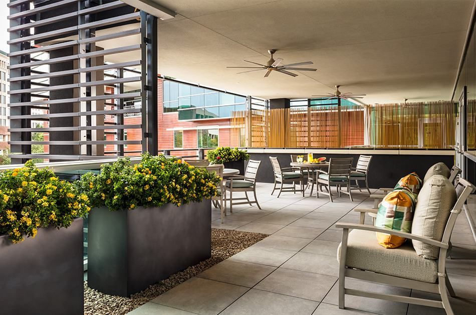 A modern outdoor patio with seating and plants, designed for a comfortable urban setting.